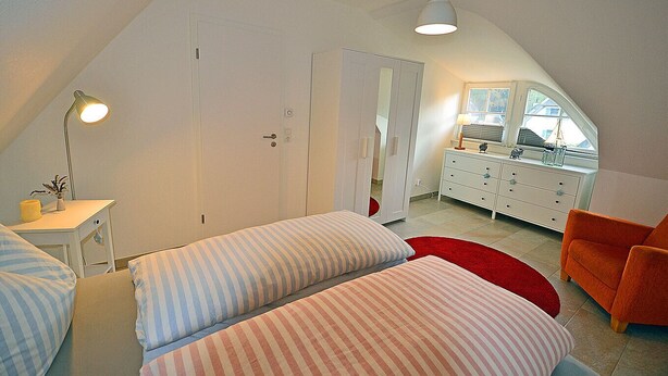 Een slaapkamer met twee bedden, een bureau, een stoel en een kast.