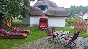 Een terras met lounge stoelen, een tafel en een gebouw met rieten dak.