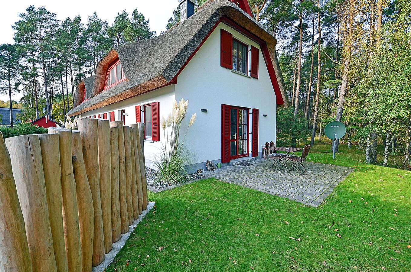 A house with a sloped roof, red shutters, and a paved patio with outdoor furniture.