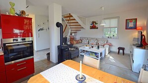 Een moderne woonkamer met een rode keuken, een trap en een eethoek.