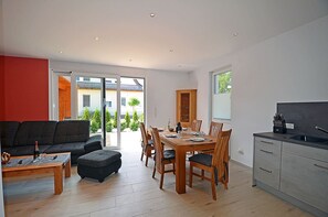 Interior moderno com área de refeições, cozinha e uma grande porta de vidro deslizante que dá para um espaço ao ar livre.