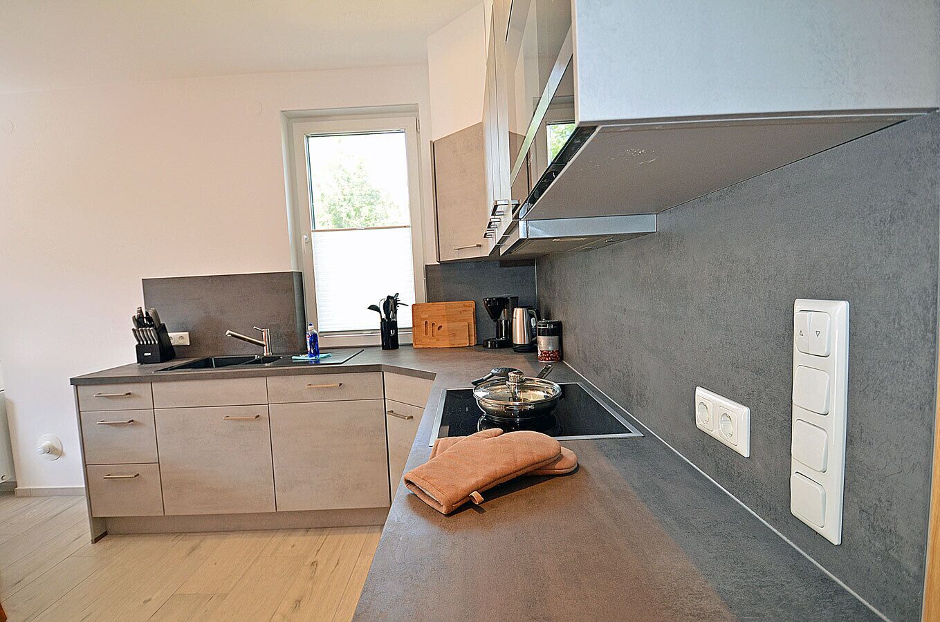 Una cocina moderna con horno empotrado, cafetera y lavabo.