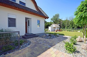 Uma casa moderna com gramado bem cuidado, um pequeno depósito e um caminho de paralelepípedos até a entrada.