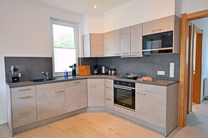 Eine moderne Küche mit Backofen, Mikrowelle und einem großen Fenster für natürliches Licht.