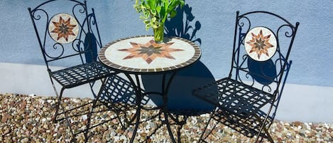 A round table with a star-patterned tile top, flanked by two chairs with decorative backs.