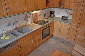 A kitchen with wooden cabinets, a built-in oven, a coffee maker, and a toaster. - Two-story vacation home with 3 bedrooms and a fireplace, about 350 meters from the sandy beach (Glowe)