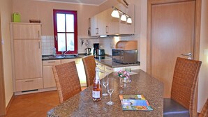 Una cocina compacta con una mesa de comedor, sillas y un refrigerador.