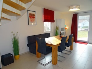 A dining area with a wooden table, chairs, a sofa, and a staircase. - Vacation home with a fireplace, about 450 meters from the sandy beach, with Wi-Fi and a washing machine (Glowe)