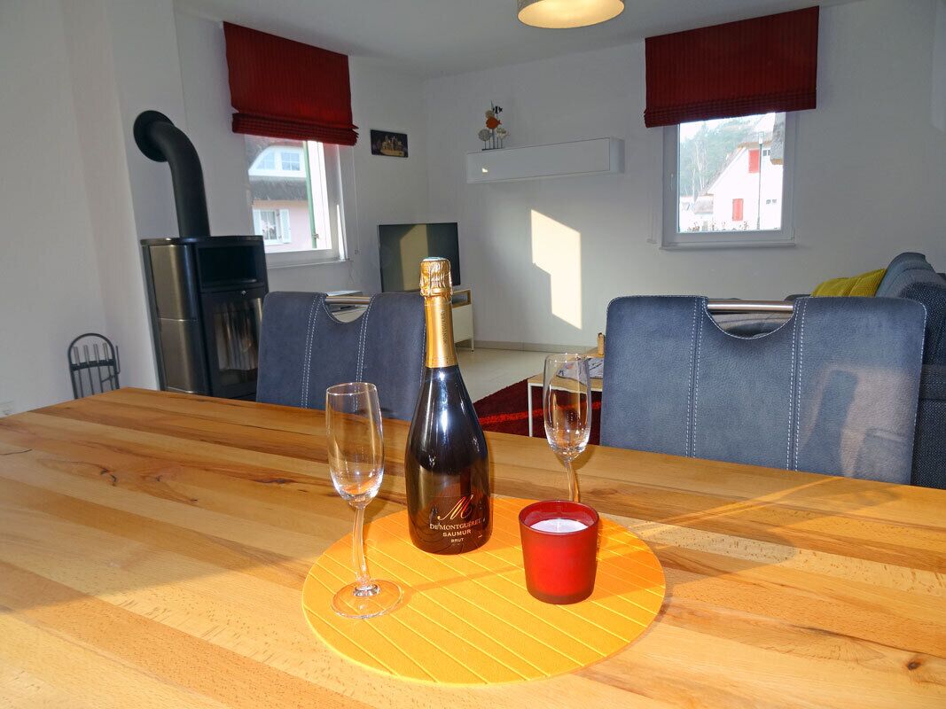 A dining table with a bottle of champagne, two glasses, and a candle.
