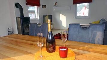 A dining table with a bottle of champagne, two glasses, and a candle.