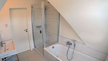 Un bagno moderno con doccia, vasca e lavabo.