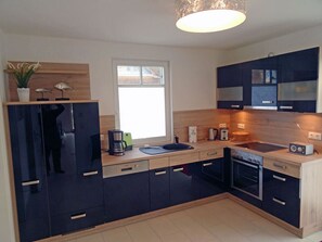 A modern kitchen with dark cabinets, a wooden countertop, and a built-in oven. - Vacation home with a fireplace, about 450 meters from the sandy beach, with Wi-Fi and a washing machine (Glowe)