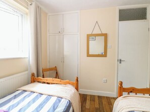 A bedroom with a bed, a chair, a wardrobe, and a mirror. - The Bungalow (Great Yarmouth)