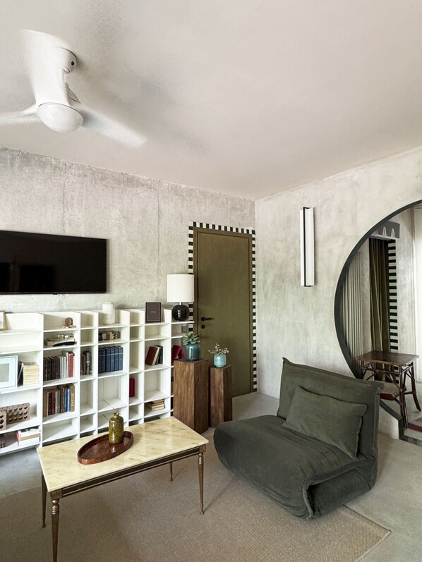 A living room with a sofa, a coffee table, a bookshelf, a flat-screen TV, and a door with a decorative frame. - La Bauhaus by Wonderful Italy (Desenzano del Garda)