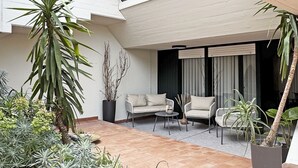 Eine moderne Außenpatio mit einer Couch, Sesseln und Topfpflanzen.