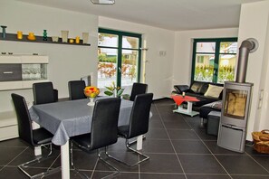 Eine moderne Küche mit Essbereich, Kamin und großen Fenstern.