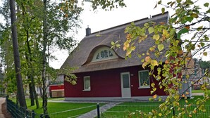 A red building with a sloped roof, a small porch, and a fenced yard. - Vacation home with a fireplace and sauna, about 300 meters from the sandy beach; pets welcome (Glowe)