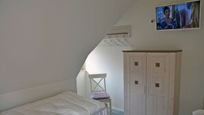 A bedroom with a bed, a chair, a wardrobe, and a television mounted on the wall. - Vacation home with a fireplace and sauna, about 300 meters from the sandy beach; pets welcome (Glowe)