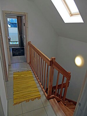 A staircase with a wooden handrail, a yellow mat at the bottom, and a skylight above. - Vacation home with a fireplace, about 800 meters from the sandy beach, Wi-Fi, dogs welcome (Glowe)