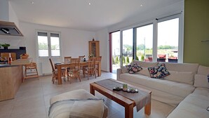 Un salon moderne comprenant un canapé, une table basse et un coin repas avec des chaises et un buffet.