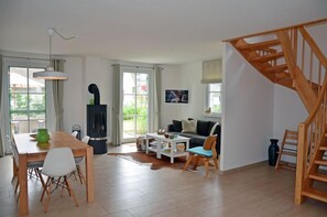 Un espace de vie moderne comprenant un coin repas, un canapé, un escalier et une cheminée.