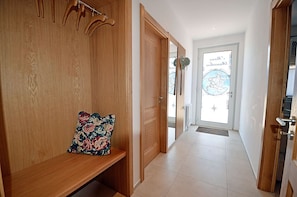A hallway with wooden walls, a bench with a floral cushion, and a door leading to a room with a globe decoration. - 2-story vacation home, quiet location, about 1.3 kilometers from the sandy beach, Wi-Fi (Glowe)