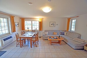 A living room with a dining table, sofa, and a coffee table. - Vacation home with a sauna, about 300 meters from the sandy beach, Wi-Fi, and a washing machine (Glowe)