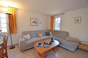 A living room with a grey sofa, a wooden coffee table, and a floor lamp. - Vacation home with a sauna, about 300 meters from the sandy beach, Wi-Fi, and a washing machine (Glowe)