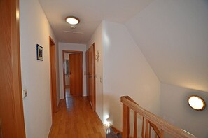 Un corridoio con pavimento in legno, ringhiera in legno e illuminazione a incasso.