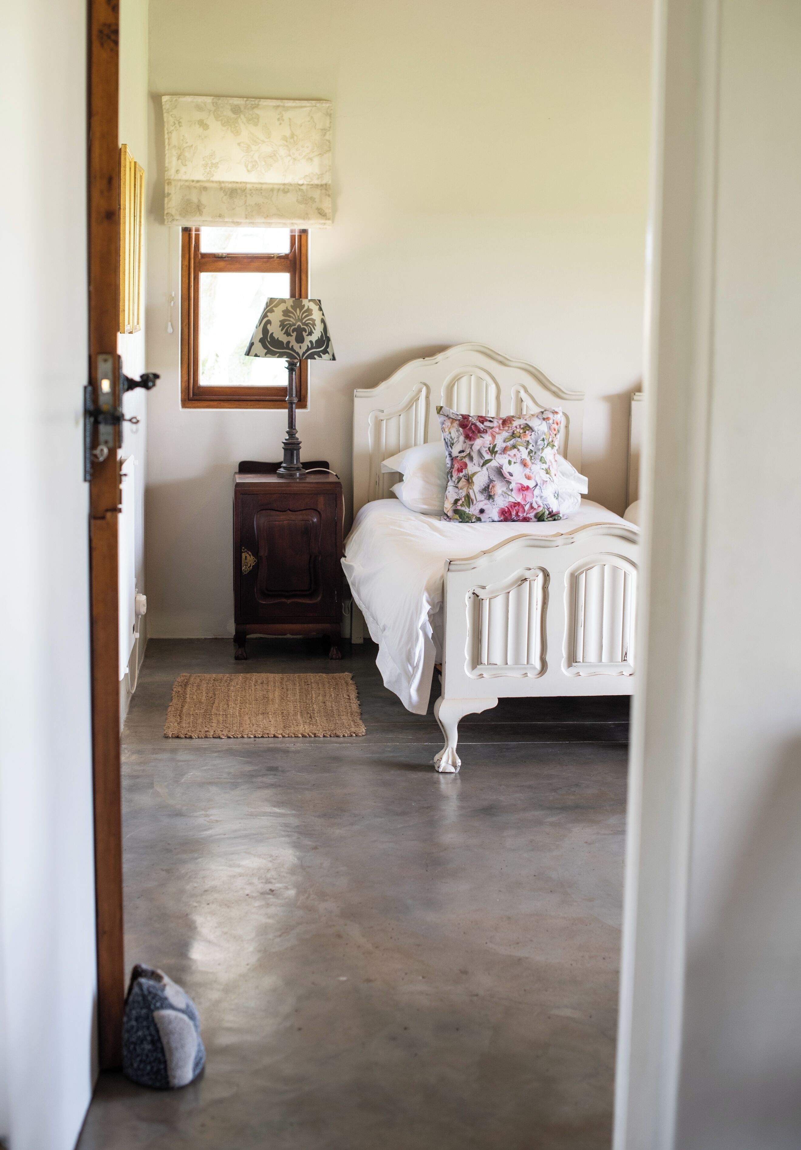 A bedroom with a bed, a nightstand, a lamp, and a window.