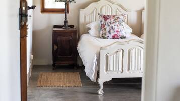 A bedroom with a bed, a nightstand, a lamp, and a window.