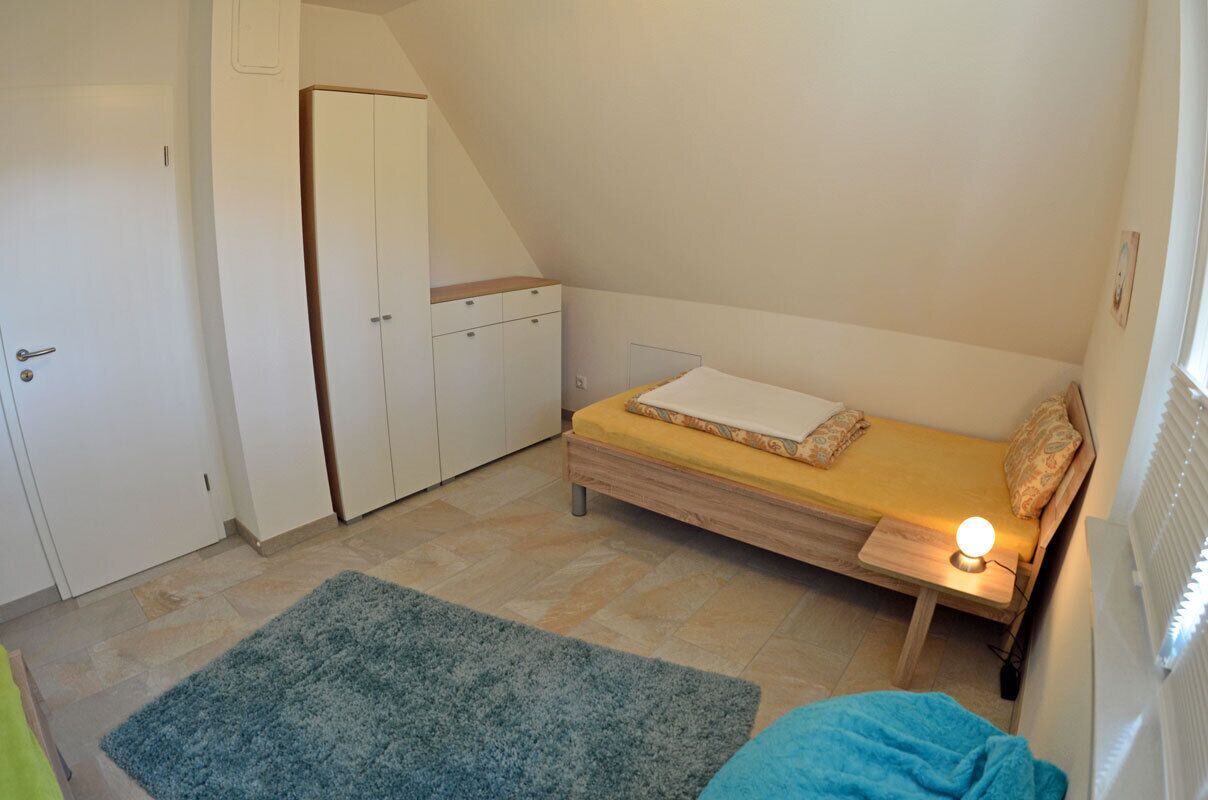 Een kleine, compacte kamer met een bed, een garderobe en een radiator.