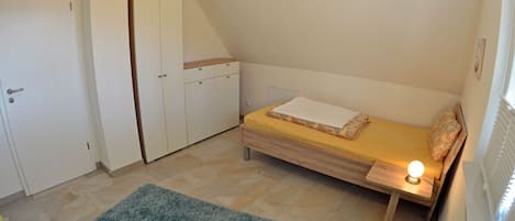 Une petite pièce, de taille modeste, comprenant un lit, une armoire et un radiateur.