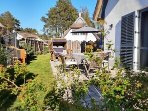 Ein Innenhof mit einem Gebäude mit Reetdach, Gartenmöbeln und einem Holzzaun.