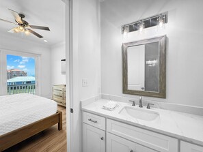 A modern bathroom with a large mirror, white vanity, and a ceiling fan. - The Fort - Gulf Coast Getaway (Gulf Shores)