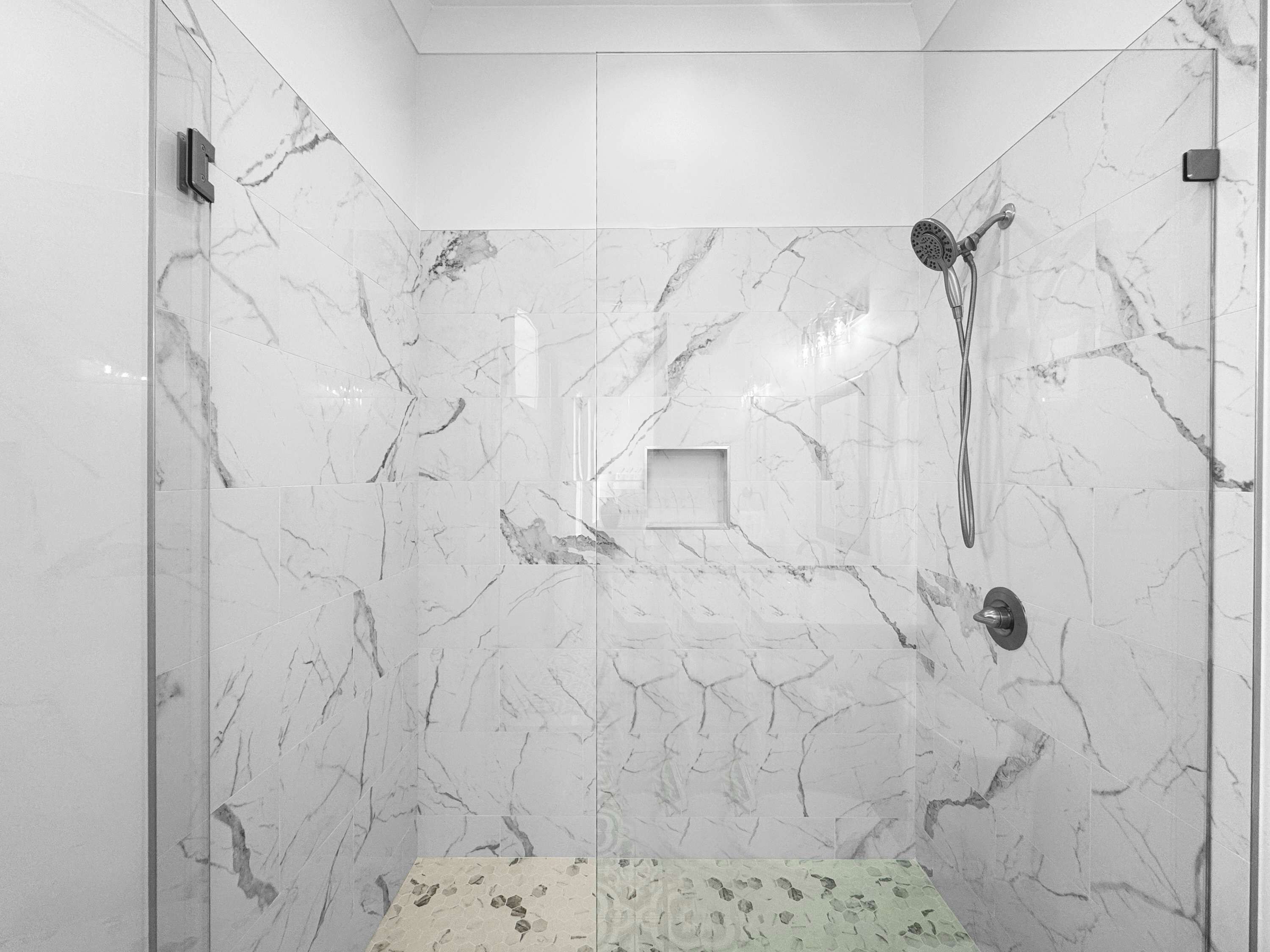 A modern shower with a handheld showerhead and a wall-mounted control.
