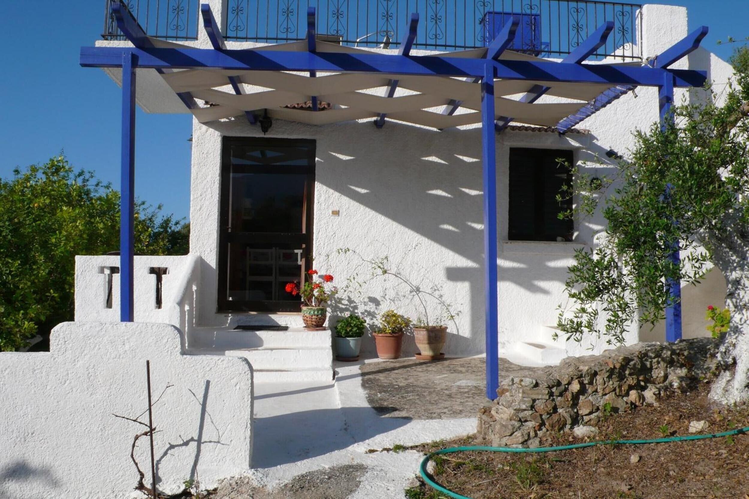 A white building with a blue balcony and a door.