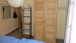 A bedroom with a bed, a wardrobe, a hanging lamp, a guitar, and a small shelf with flowers. - Vacation rental, very quiet location, about 350 m from the sandy beach (Baltic Sea), Wi-Fi (Glowe)