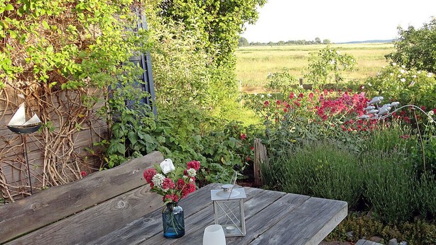 A wooden table with a vase of flowers and two candle holders. - Vacation rental, very quiet location, about 350 m from the sandy beach (Baltic Sea), Wi-Fi (Glowe)