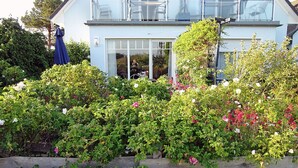 A house with a balcony, a wooden fence, and a variety of flowering plants. - Vacation rental, very quiet location, about 350 m from the sandy beach (Baltic Sea), Wi-Fi (Glowe)
