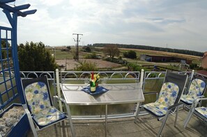 An outdoor patio with a table and chairs, a bottle of champagne, and a view of the countryside. - Vacation rental, very quiet location, about 390 m from the sandy beach (Baltic Sea), Wi-Fi (Glowe)