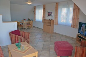 Ein Wohnzimmer mit Essbereich, Fernseher und einer Couch.
