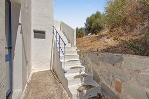 Eine Treppe führt zu einem Gebäude, dessen eine Seite eine Steinmauer und die andere eine weiße Mauer aufweist.