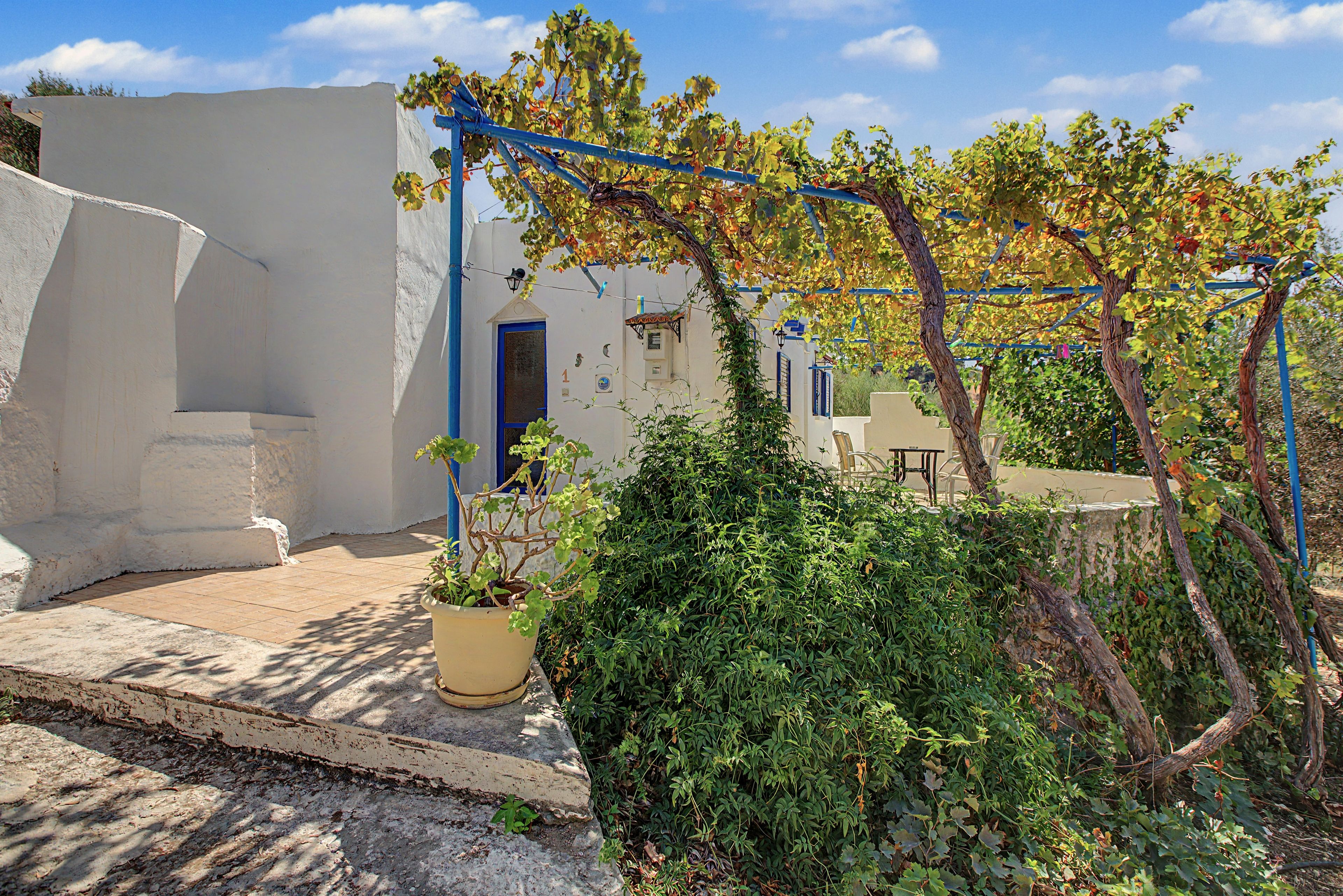 A courtyard with a white building, a blue door, and a table.