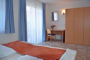 A bedroom with a bed, a desk, a chair, a wardrobe, and a window with curtains. - Vacation rental, very quiet location, about 400 m from the sandy beach (Baltic Sea), Wi-Fi (Glowe)