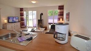 A kitchen with a coffee maker, toaster, and a television on a cabinet. - Just 500 meters from the sandy Baltic Sea beach, Wi-Fi, and a washing machine with a covered patio (Glowe)