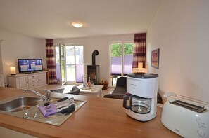 A kitchen with a coffee maker, toaster, and a television on a cabinet. - Just 500 meters from the sandy Baltic Sea beach, Wi-Fi, and a washing machine with a covered patio (Glowe)