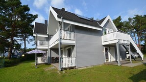A two-story house with a balcony on the upper floor, a covered porch on the lower floor, and a staircase leading to the upper floor. - Just 500 meters from the sandy Baltic Sea beach, Wi-Fi, and a washing machine with a covered patio (Glowe)