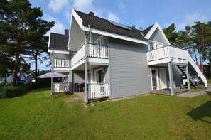 A two-story house with a balcony on the upper floor, a covered porch on the lower floor, and a staircase leading to the upper floor. - Just 500 meters from the sandy Baltic Sea beach, Wi-Fi, and a washing machine with a covered patio (Glowe)