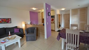 A living room with a sofa, a coffee table, and a dining table with chairs. There is a kitchen area with cabinets and a microwave. - Just 500 meters from the sandy Baltic Sea beach, Wi-Fi, and a washing machine with a covered patio (Glowe)